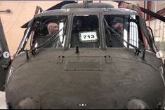 The nose end of an Army helicopter with two soldiers sitting inside.